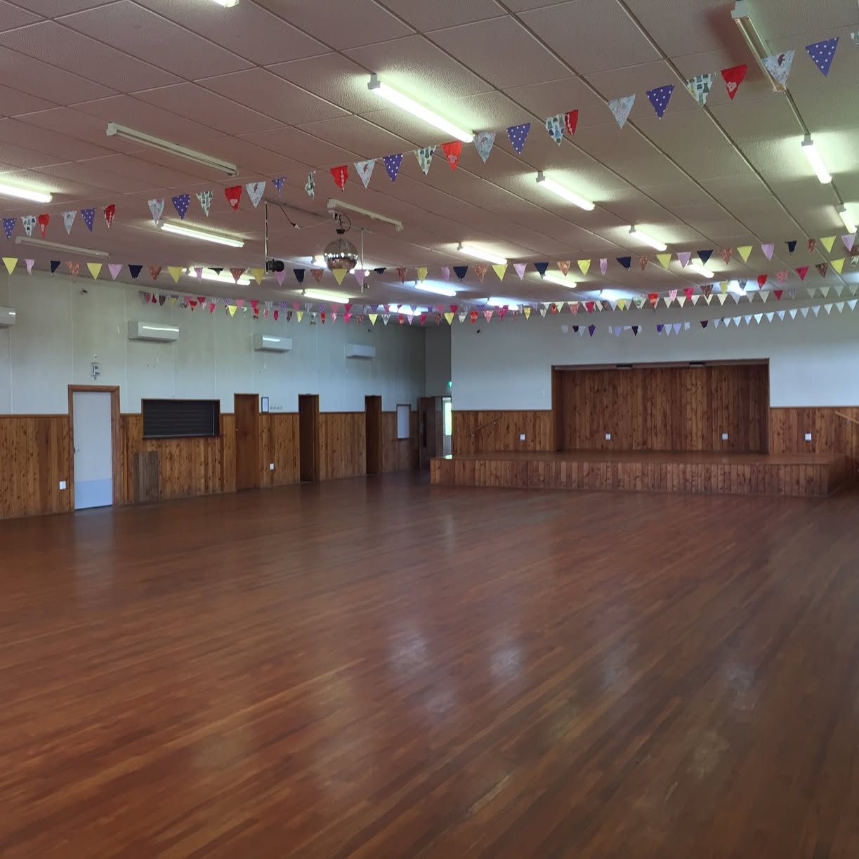 Wingatui Hall's open timber floor and raised stage, with bunting overhead